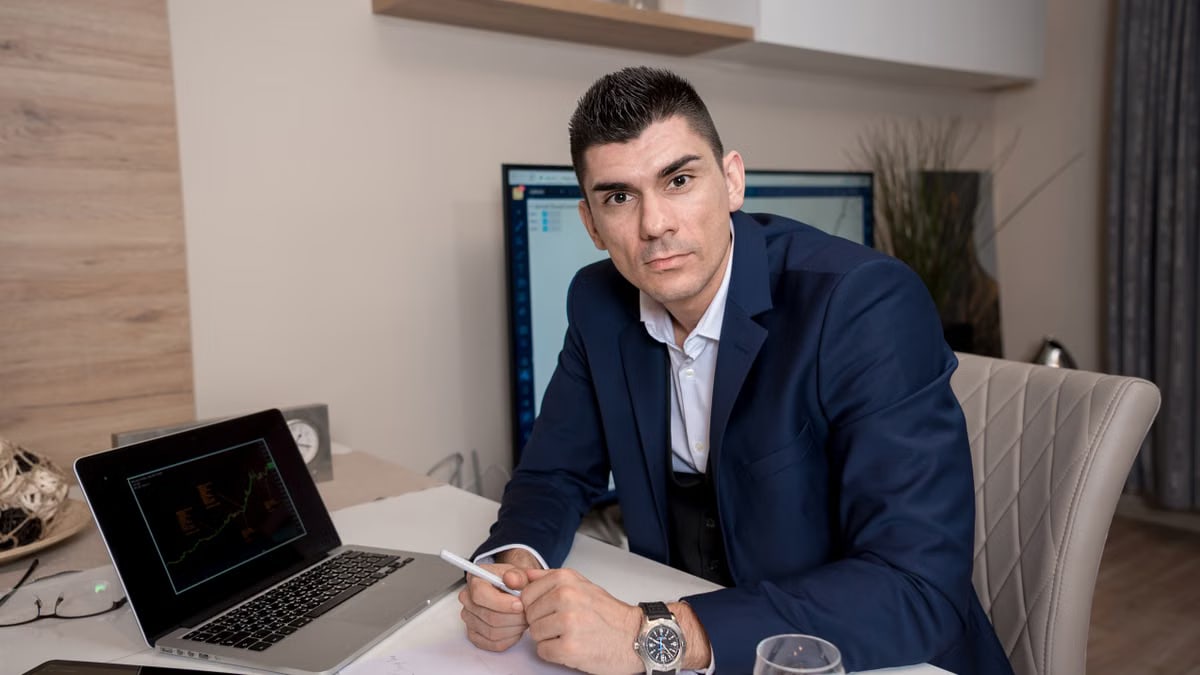 Businessman in blue suit working on laptop in sleek office setting, conveying professionalism and focus.